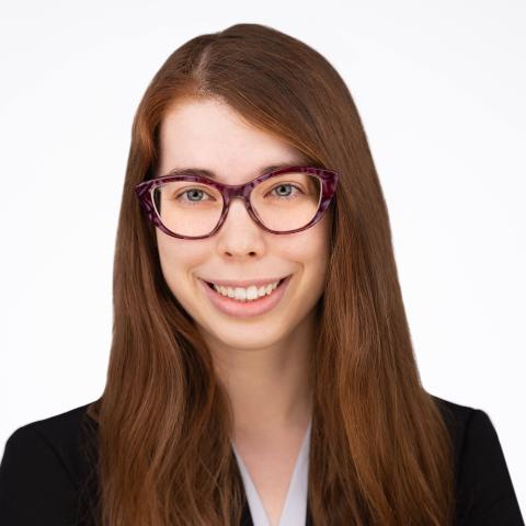 A woman with glasses in front of a white background.